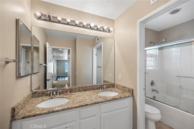 full bathroom featuring vanity, combined bath / shower with glass door, and toilet