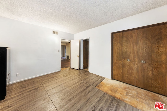 unfurnished bedroom with a closet, hardwood / wood-style floors, and a textured ceiling