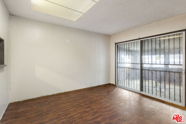 unfurnished room with dark hardwood / wood-style flooring and a textured ceiling