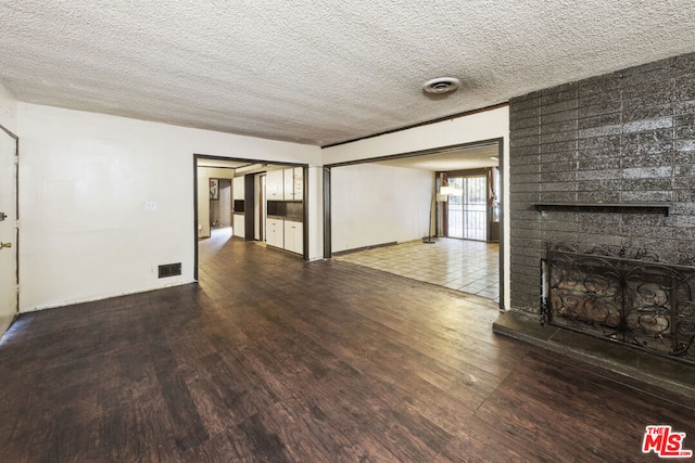 unfurnished living room with hardwood / wood-style floors, a fireplace, and a textured ceiling