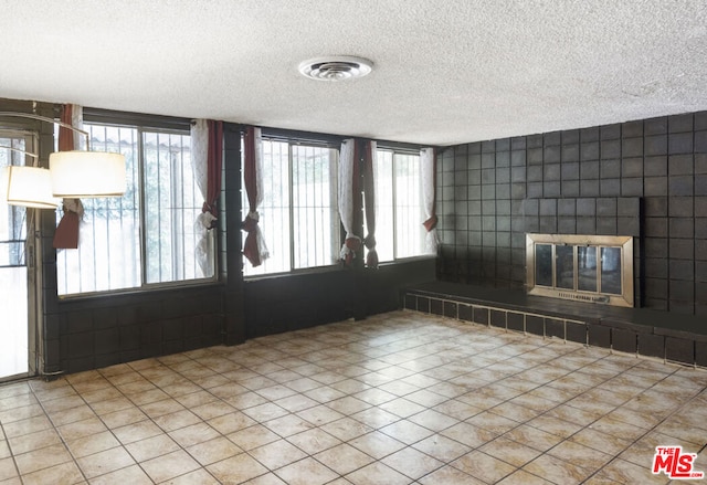 interior space featuring a tiled fireplace, light tile patterned floors, and a textured ceiling