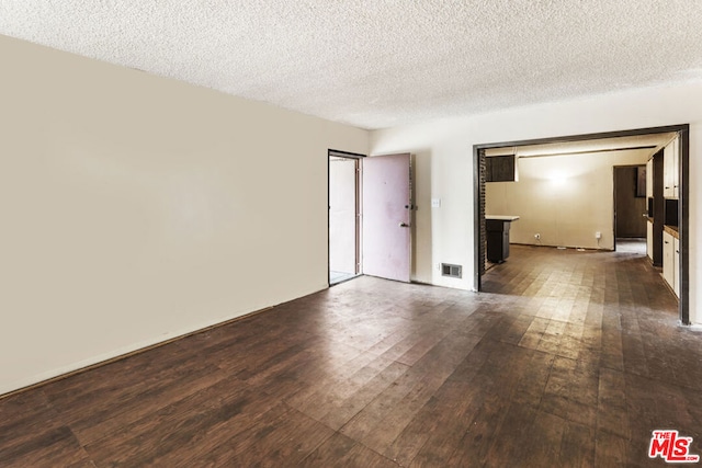 unfurnished room with a textured ceiling and dark wood-type flooring