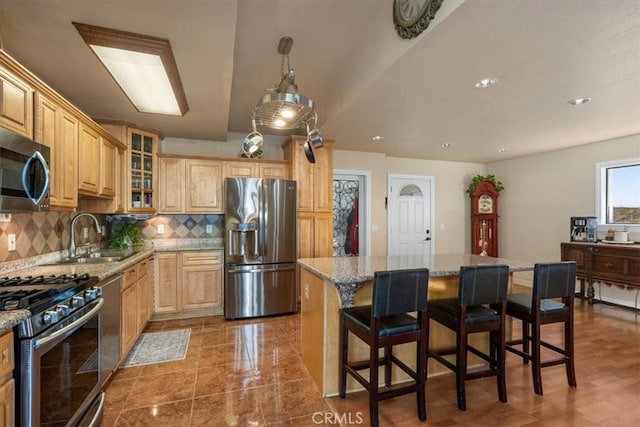 kitchen with decorative backsplash, light stone counters, appliances with stainless steel finishes, and a sink