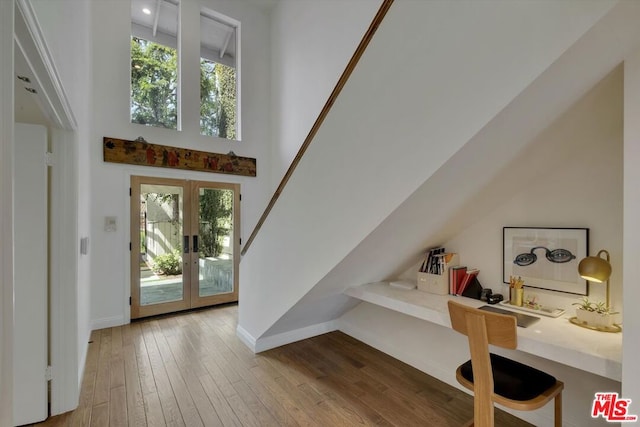 entrance foyer featuring a high ceiling, light hardwood / wood-style flooring, french doors, and a healthy amount of sunlight