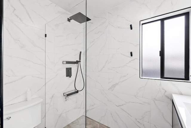 bathroom featuring a tile shower, vanity, and toilet