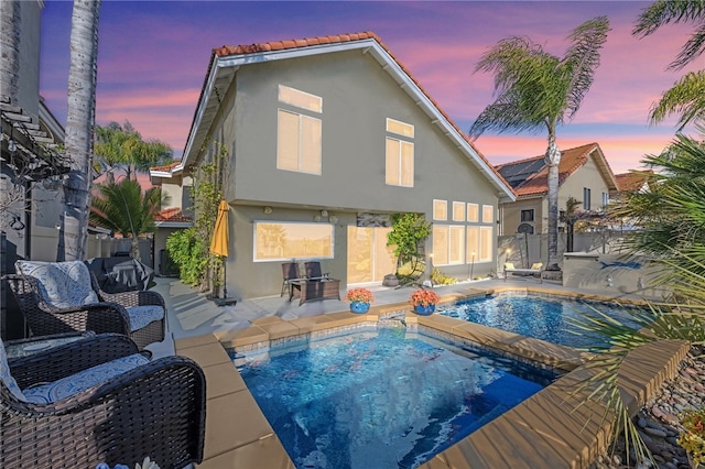 back house at dusk featuring a patio area and a hot tub