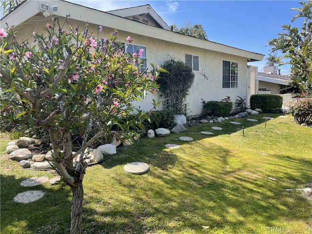 view of property exterior featuring a lawn and stucco siding