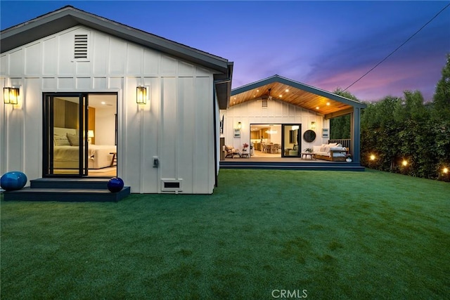 back house at dusk featuring a lawn