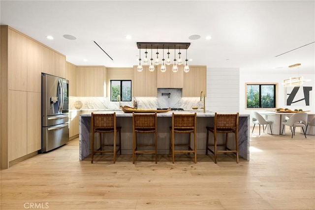 kitchen featuring stainless steel fridge with ice dispenser, light countertops, decorative backsplash, light brown cabinetry, and modern cabinets