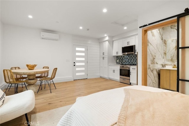 interior space featuring tasteful backsplash, stainless steel appliances, white cabinets, and light wood-type flooring