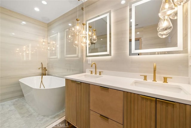 full bath featuring a freestanding bath, double vanity, a sink, and tile walls