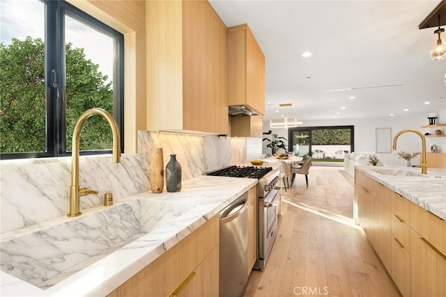 kitchen featuring light brown cabinetry, modern cabinets, a sink, and stainless steel appliances