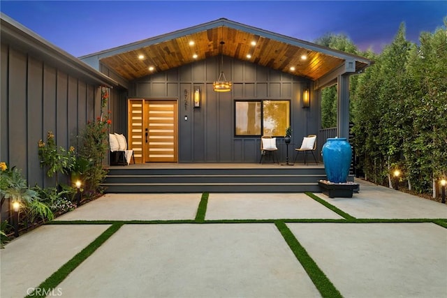 exterior entry at dusk with board and batten siding and a patio