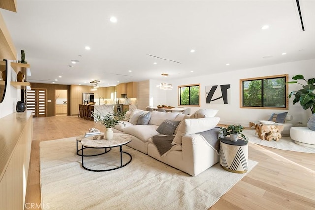 living area with an inviting chandelier, light wood-style flooring, and recessed lighting