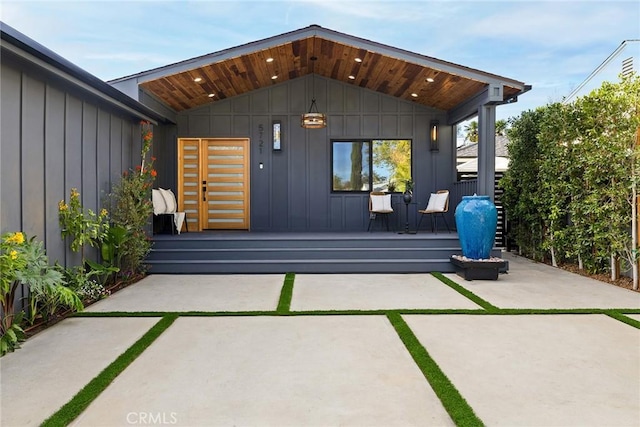 back of house with covered porch, a patio area, and board and batten siding