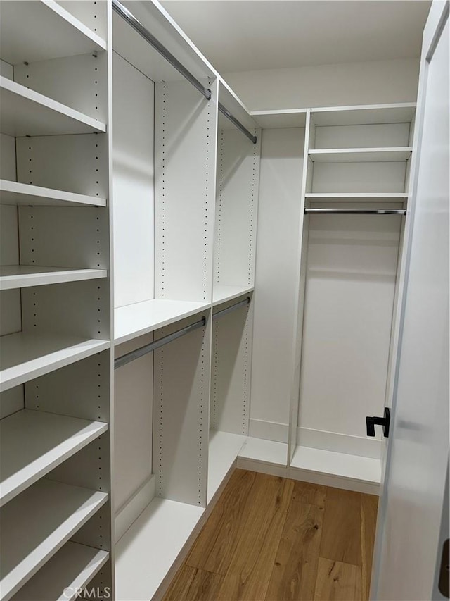 walk in closet with wood finished floors