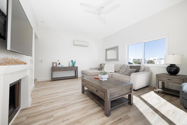 living room with a wall mounted air conditioner, ceiling fan, and light hardwood / wood-style flooring