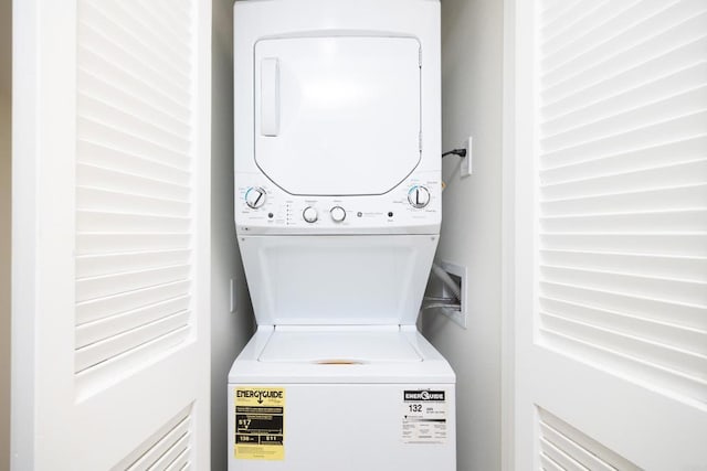 clothes washing area with stacked washing maching and dryer