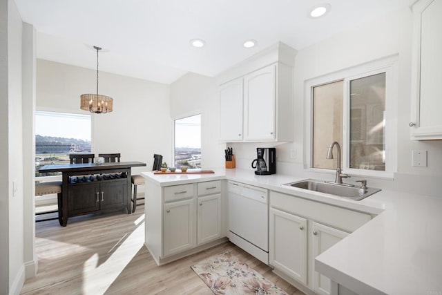 kitchen featuring kitchen peninsula, white dishwasher, sink, pendant lighting, and white cabinetry