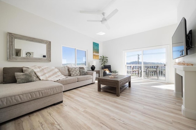 living room featuring plenty of natural light, ceiling fan, light wood-type flooring, and a fireplace