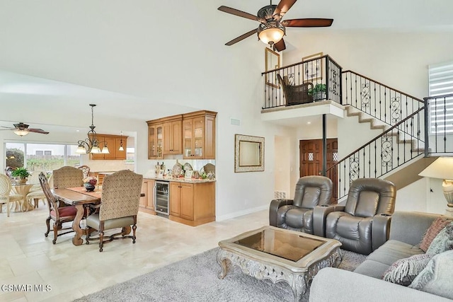 living room with wine cooler, a high ceiling, and ceiling fan with notable chandelier