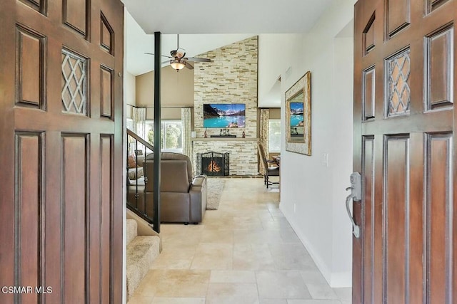 tiled foyer with high vaulted ceiling, a stone fireplace, and ceiling fan