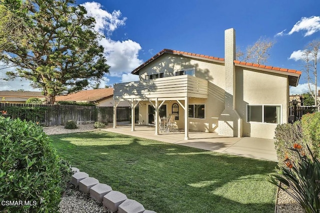 rear view of property featuring a balcony, a patio area, and a lawn