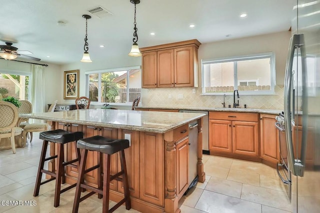 kitchen with ceiling fan, a kitchen island, a wealth of natural light, and stainless steel refrigerator