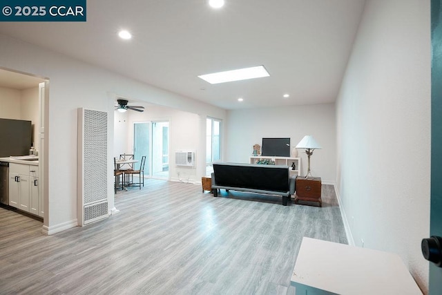 living room with ceiling fan, a wall mounted air conditioner, and light wood-type flooring