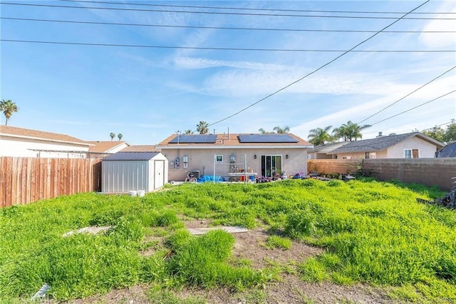 back of house featuring solar panels and a storage shed