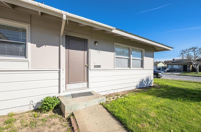 view of exterior entry with a yard