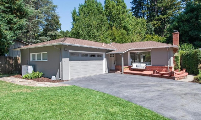 ranch-style home featuring a front yard, an outdoor hangout area, a garage, and cooling unit