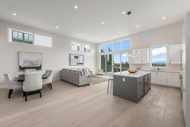 kitchen featuring a kitchen island, sink, pendant lighting, light hardwood / wood-style floors, and white cabinetry