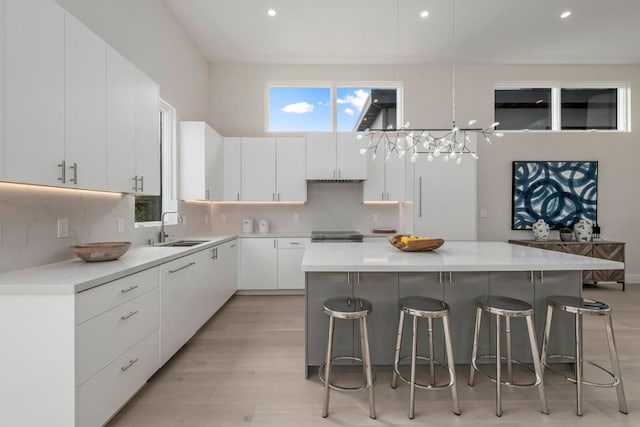 kitchen with a kitchen bar, a center island, white cabinets, and sink