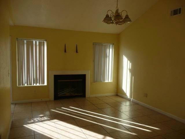 unfurnished living room featuring a notable chandelier and tile patterned floors