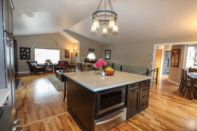 kitchen with built in microwave, decorative light fixtures, light wood-type flooring, and a kitchen island