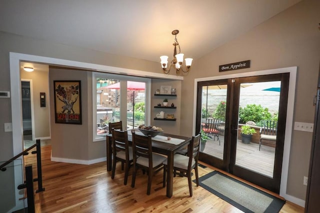 dining area featuring an inviting chandelier, vaulted ceiling, french doors, and wood-type flooring