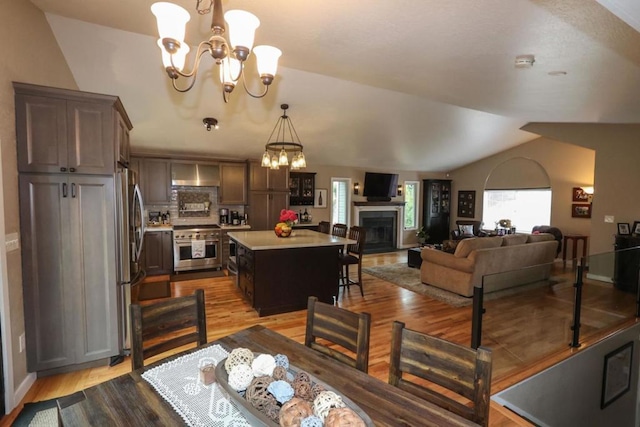 dining room featuring vaulted ceiling, light hardwood / wood-style floors, a chandelier, and plenty of natural light