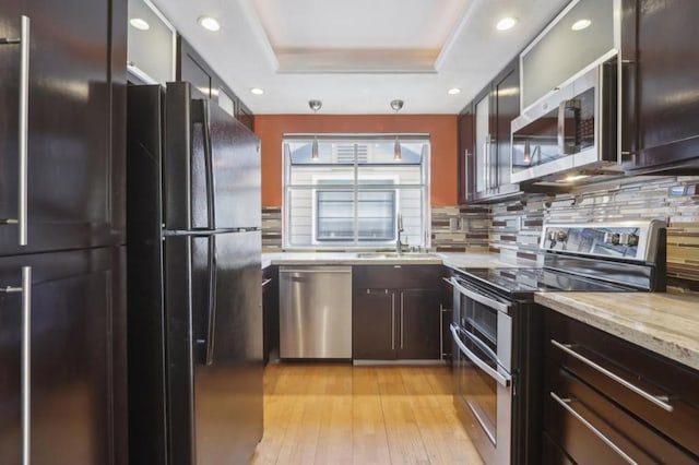 kitchen with sink, decorative backsplash, a tray ceiling, and appliances with stainless steel finishes