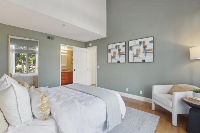 bedroom featuring ensuite bathroom and light hardwood / wood-style flooring