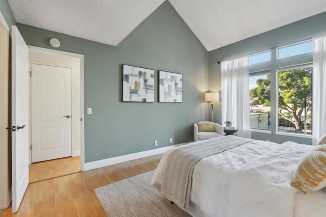 bedroom with multiple windows, light hardwood / wood-style flooring, and lofted ceiling