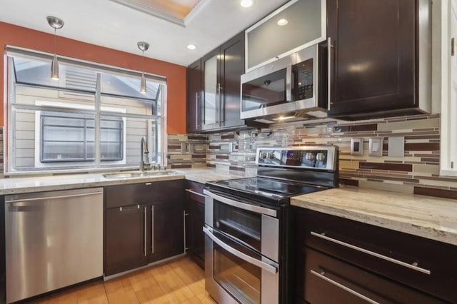 kitchen featuring light stone countertops, sink, pendant lighting, and appliances with stainless steel finishes