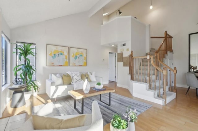 living room featuring high vaulted ceiling and light hardwood / wood-style flooring