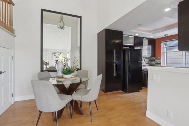 dining room featuring a raised ceiling and light hardwood / wood-style flooring