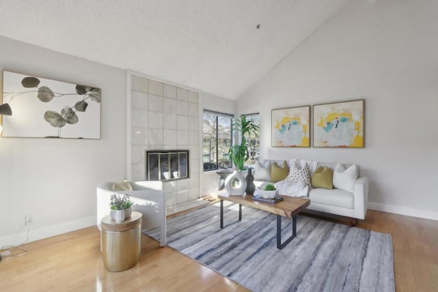 living room featuring high vaulted ceiling, wood-type flooring, and a fireplace