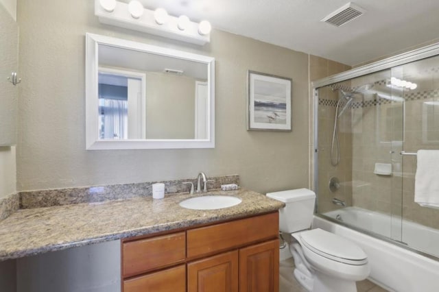 full bathroom with bath / shower combo with glass door, toilet, and vanity