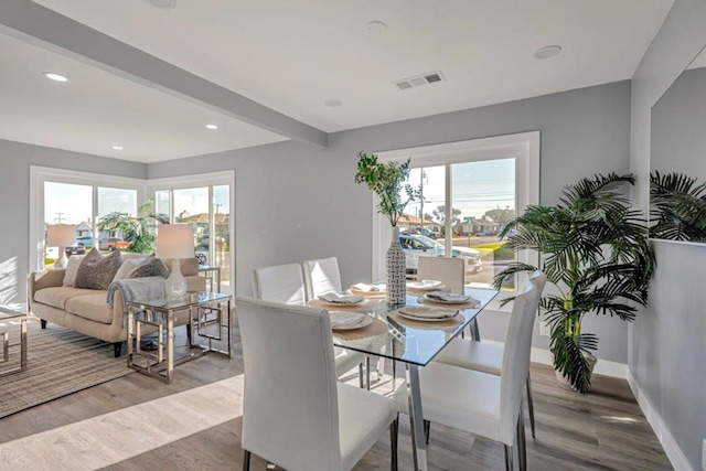 dining area featuring beam ceiling and light hardwood / wood-style flooring