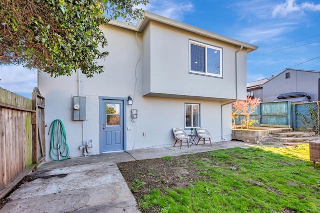 rear view of house with a lawn and a patio