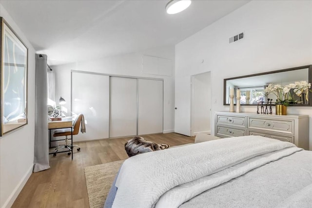 bedroom featuring light wood-type flooring, vaulted ceiling, and a closet