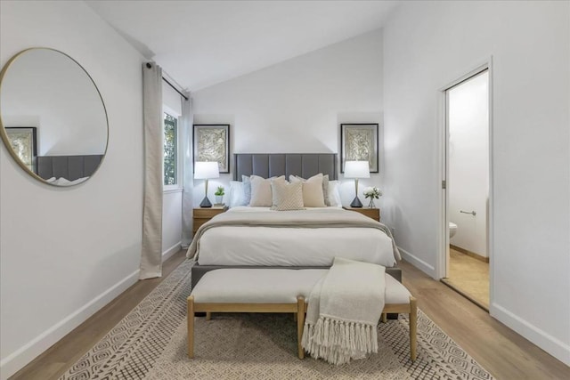 bedroom featuring connected bathroom, lofted ceiling, and light hardwood / wood-style floors